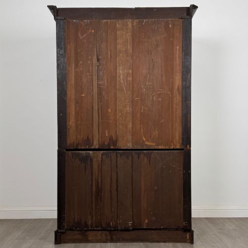 fig 5. A tall 19th-century dark mahogany linen press featuring carved panelled doors on top and a chest of four drawers at the base.