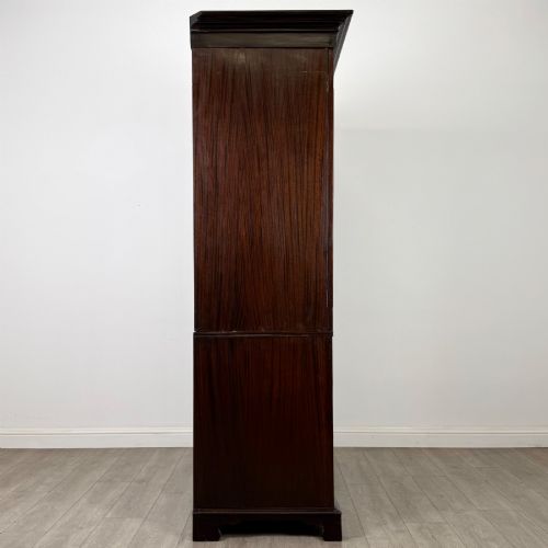 fig 7. A tall 19th-century dark mahogany linen press featuring carved panelled doors on top and a chest of four drawers at the base.