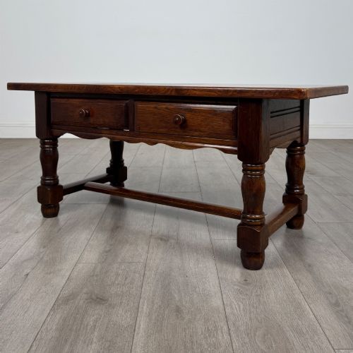 fig 1. A dark oak rectangular coffee table featuring two front drawers with wooden knob handles and turned baluster legs connected by a low stretcher.