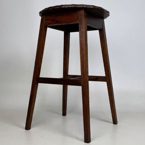 fig 1. A tall, dark oak Edwardian side table featuring a scalloped piecrust rim top, four splayed square legs, and a lower slatted shelf.
