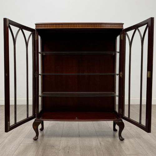 fig 1. An Edwardian mahogany display cabinet featuring astragal glazed doors with gothic arches, interior glass shelves, and cabriole legs.