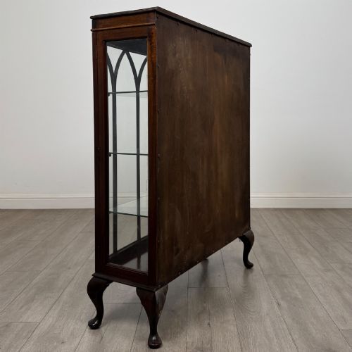 fig 4. An Edwardian mahogany display cabinet featuring astragal glazed doors with gothic arches, interior glass shelves, and cabriole legs.