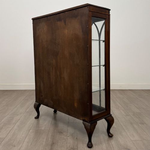 fig 6. An Edwardian mahogany display cabinet featuring astragal glazed doors with gothic arches, interior glass shelves, and cabriole legs.