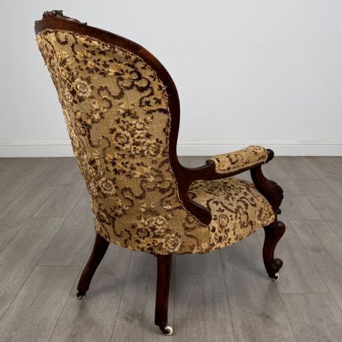 fig 4. A 19th-century Victorian open armchair constructed from carved walnut wood and upholstered in a patterned gold and brown velvet fabric.