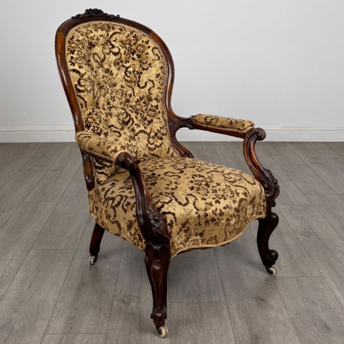fig 6. A 19th-century Victorian open armchair constructed from carved walnut wood and upholstered in a patterned gold and brown velvet fabric.