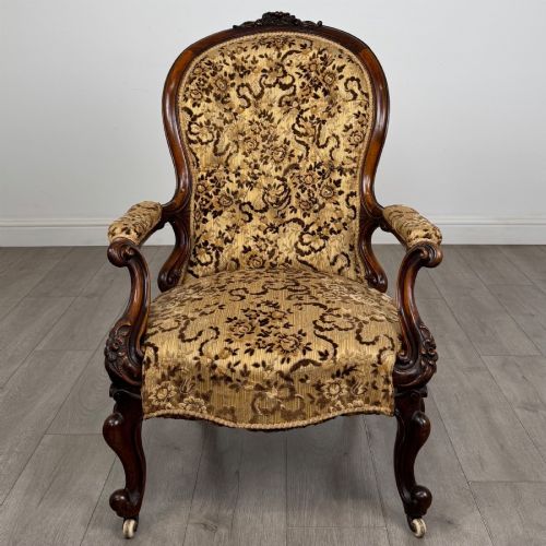 fig 7. A 19th-century Victorian open armchair constructed from carved walnut wood and upholstered in a patterned gold and brown velvet fabric.