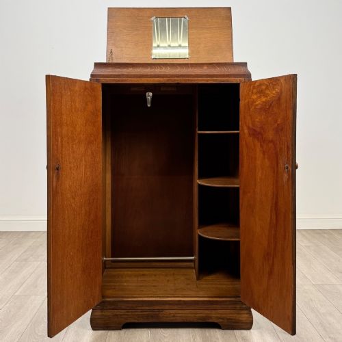 fig 1. A compact 20th-century oak fitted wardrobe with two doors featuring diagonal grain veneering, turned wooden knobs, and a stepped top profile.