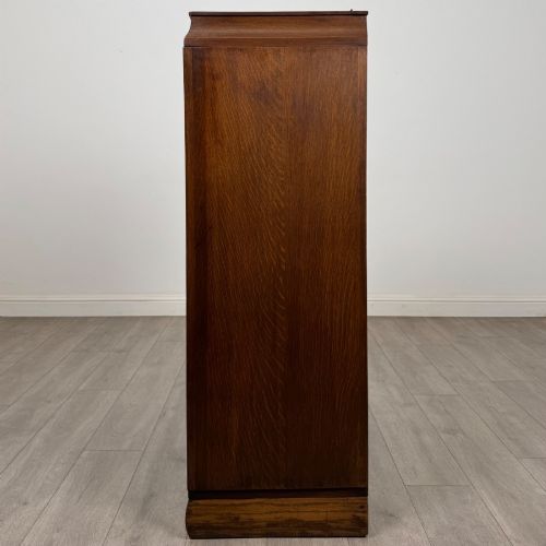 fig 3. A compact 20th-century oak fitted wardrobe with two doors featuring diagonal grain veneering, turned wooden knobs, and a stepped top profile.