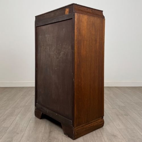 fig 6. A compact 20th-century oak fitted wardrobe with two doors featuring diagonal grain veneering, turned wooden knobs, and a stepped top profile.