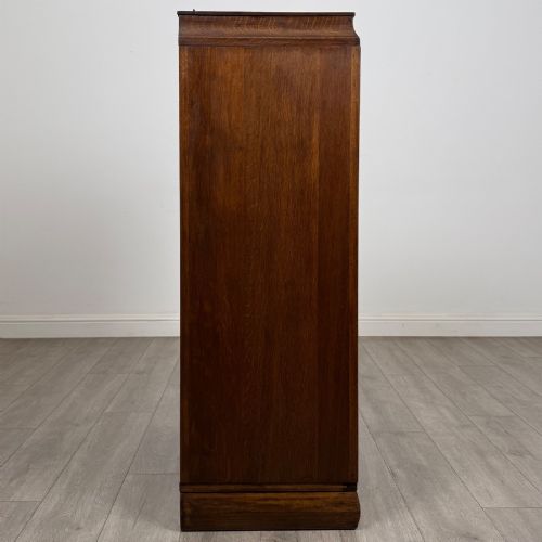 fig 7. A compact 20th-century oak fitted wardrobe with two doors featuring diagonal grain veneering, turned wooden knobs, and a stepped top profile.