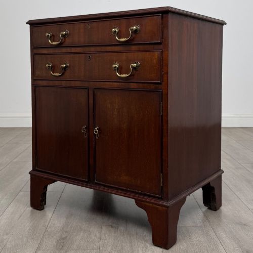 fig 2. A nineteenth-century dark mahogany small cupboard featuring two drawers with brass swan-neck handles above a double-door compartment set on bracket feet.