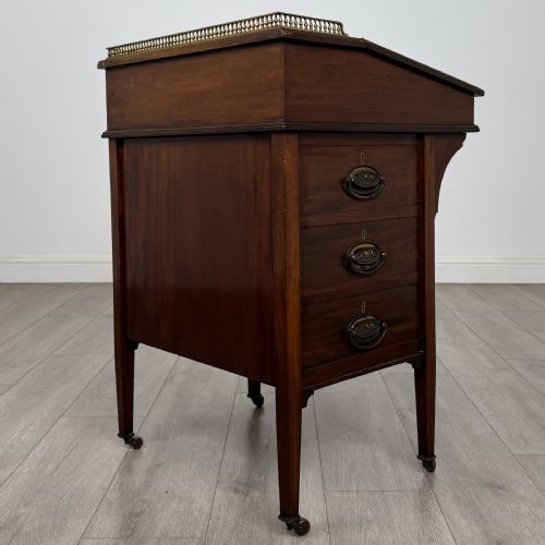 fig 4. An Edwardian mahogany Davenport desk featuring satinwood crossbanding, a top brass gallery rail, and castors on the base.
