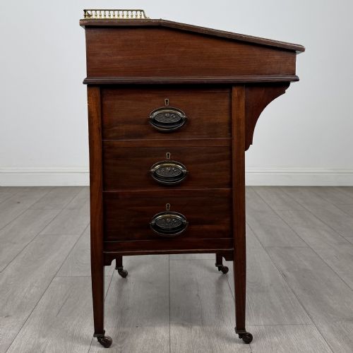 fig 5. An Edwardian mahogany Davenport desk featuring satinwood crossbanding, a top brass gallery rail, and castors on the base.