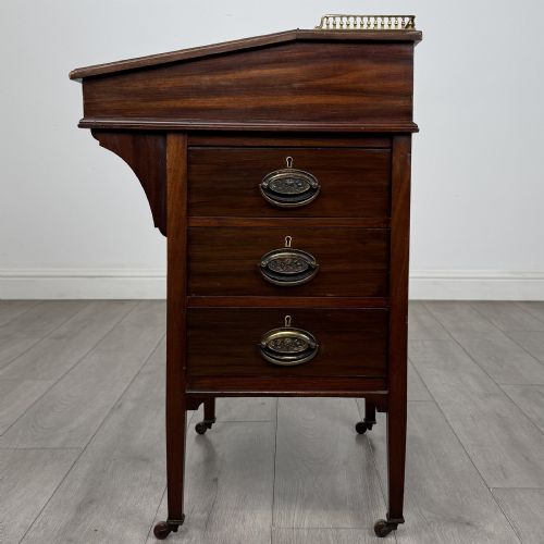 fig 1. An Edwardian mahogany Davenport desk featuring satinwood crossbanding, a top brass gallery rail, and castors on the base.