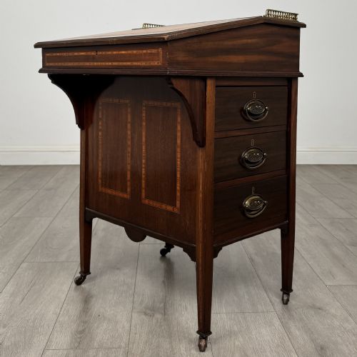 fig 7. An Edwardian mahogany Davenport desk featuring satinwood crossbanding, a top brass gallery rail, and castors on the base.