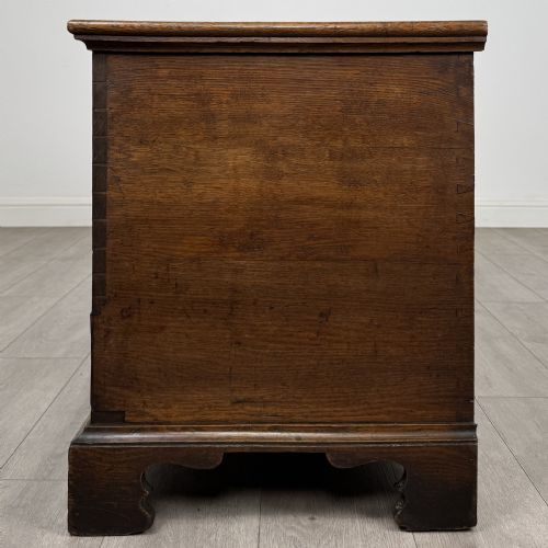 fig 2. An 18th-century Georgian golden oak mule chest featuring a hinged lid, two lower drawers with brass drop handles, shaped bracket feet, and the inscribed date 1789.