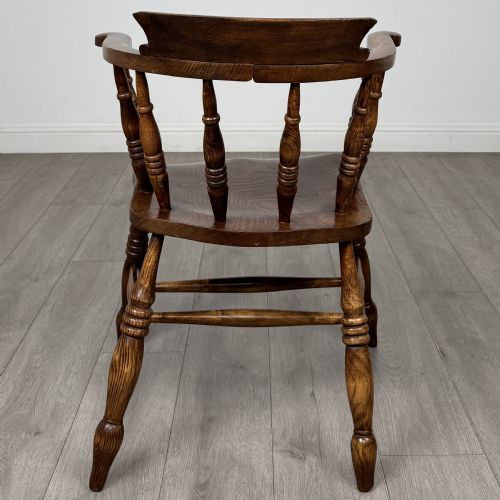 fig 3. A 20th-century antique elm smokers bow armchair featuring a horseshoe-shaped top rail, turned spindles, a shaped solid elm seat, and turned legs with H-stretchers.