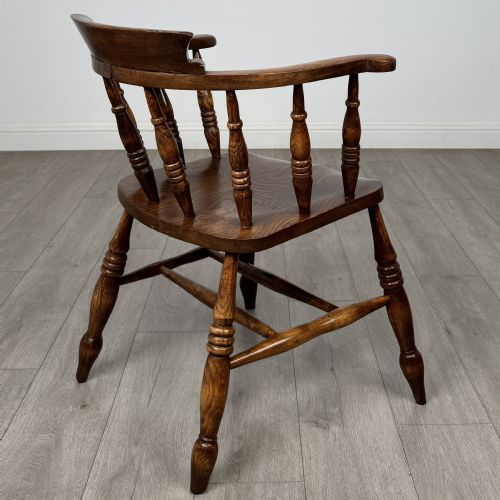 fig 4. A 20th-century antique elm smokers bow armchair featuring a horseshoe-shaped top rail, turned spindles, a shaped solid elm seat, and turned legs with H-stretchers.