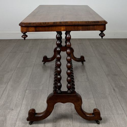 fig 2. A Victorian dark wood side table with a polished rectangular top, corner drop finials, double bobbin-turned legs, a twin bobbin stretcher, and splayed feet with brass castors.