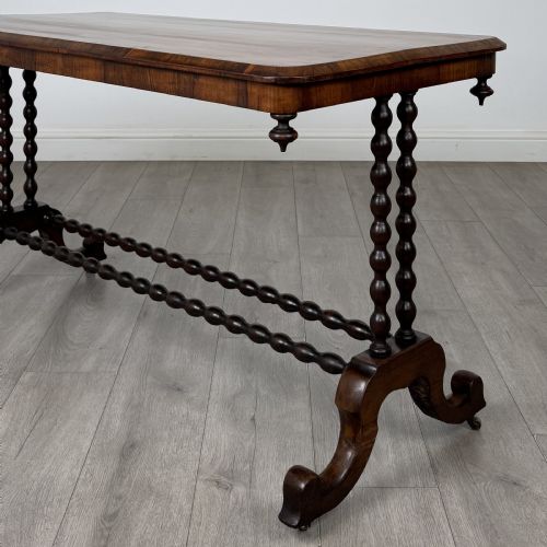 fig 4. A Victorian dark wood side table with a polished rectangular top, corner drop finials, double bobbin-turned legs, a twin bobbin stretcher, and splayed feet with brass castors.