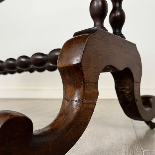 fig 5. A Victorian dark wood side table with a polished rectangular top, corner drop finials, double bobbin-turned legs, a twin bobbin stretcher, and splayed feet with brass castors.