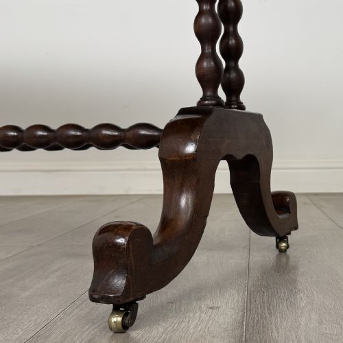 fig 6. A Victorian dark wood side table with a polished rectangular top, corner drop finials, double bobbin-turned legs, a twin bobbin stretcher, and splayed feet with brass castors.