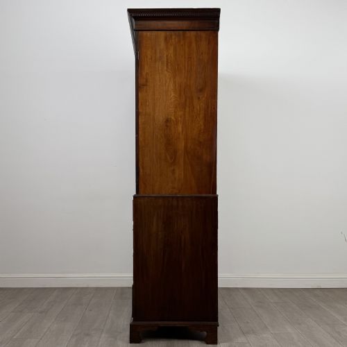 fig 3. An 18th-century Georgian mahogany linen press featuring flame mahogany door panels above four drawers with brass handles and bracket feet.