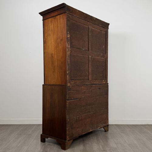 fig 4. An 18th-century Georgian mahogany linen press featuring flame mahogany door panels above four drawers with brass handles and bracket feet.