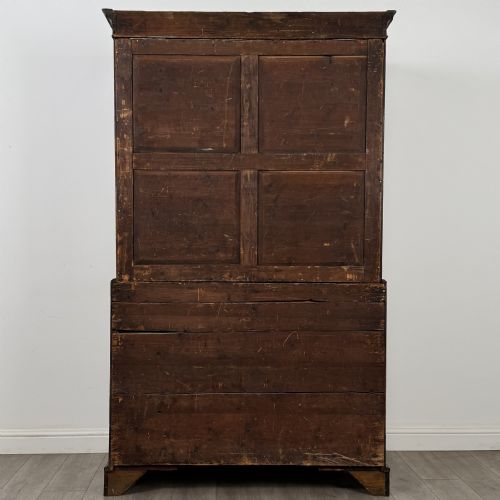 fig 5. An 18th-century Georgian mahogany linen press featuring flame mahogany door panels above four drawers with brass handles and bracket feet.