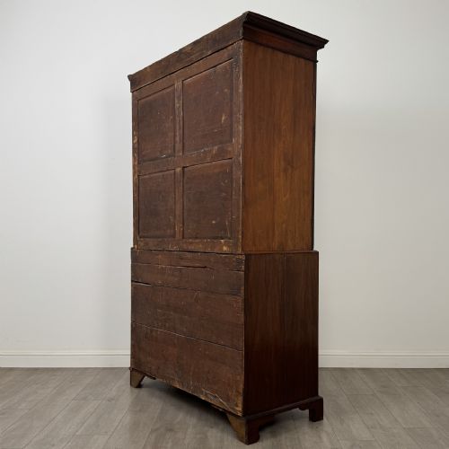fig 6. An 18th-century Georgian mahogany linen press featuring flame mahogany door panels above four drawers with brass handles and bracket feet.