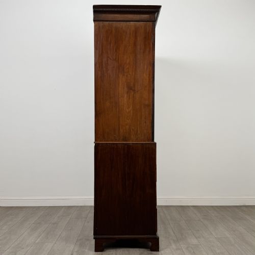 fig 7. An 18th-century Georgian mahogany linen press featuring flame mahogany door panels above four drawers with brass handles and bracket feet.