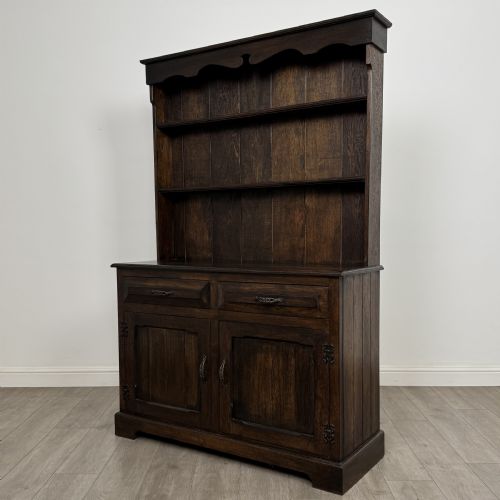 fig 2. A dark oak Welsh dresser featuring an upper plate rack with open shelves set above a two-drawer, two-door base cabinet.