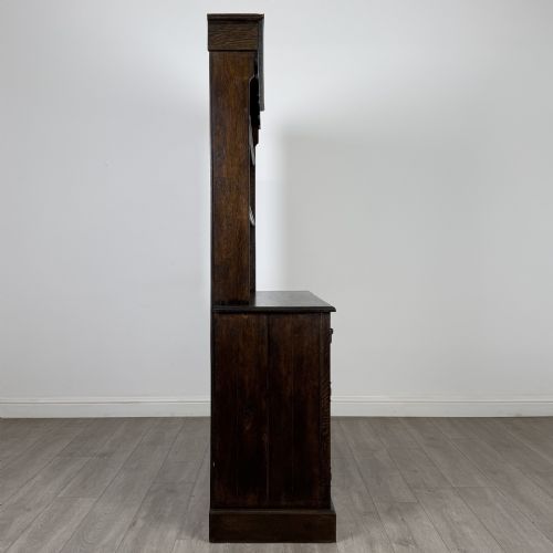 fig 7. A dark oak Welsh dresser featuring an upper plate rack with open shelves set above a two-drawer, two-door base cabinet.