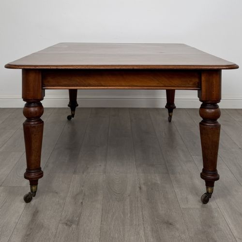 fig 1. A 19th-century Victorian mahogany dining table featuring turned legs fitted with brass castors and a rectangular top with rounded corners.