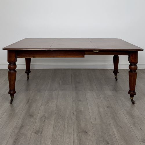 fig 2. A 19th-century Victorian mahogany dining table featuring turned legs fitted with brass castors and a rectangular top with rounded corners.