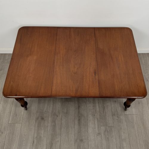 fig 5. A 19th-century Victorian mahogany dining table featuring turned legs fitted with brass castors and a rectangular top with rounded corners.