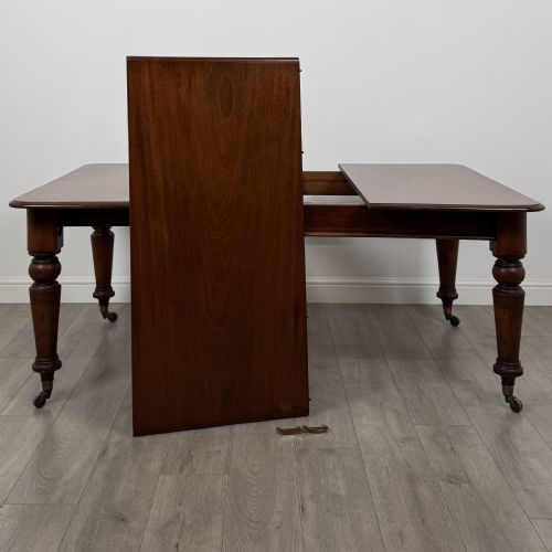 fig 6. A 19th-century Victorian mahogany dining table featuring turned legs fitted with brass castors and a rectangular top with rounded corners.