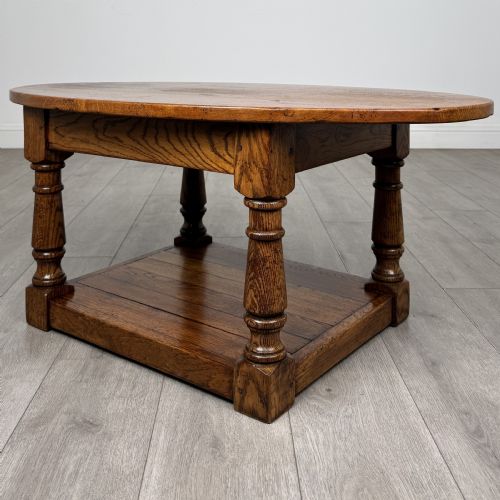 fig 1. An antique oval oak coffee table featuring four turned baluster legs and a solid lower undertier shelf.
