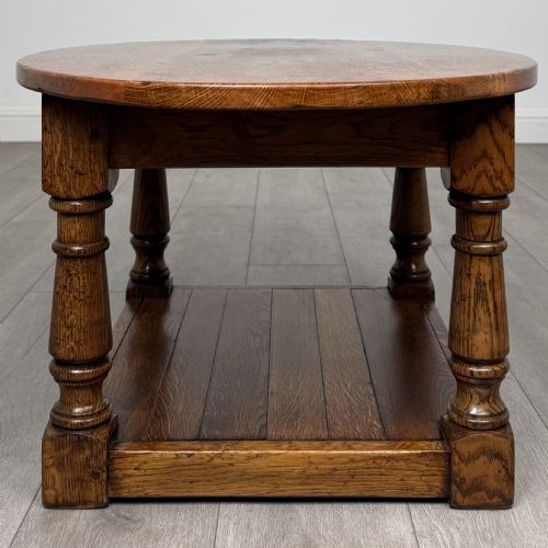 fig 2. An antique oval oak coffee table featuring four turned baluster legs and a solid lower undertier shelf.