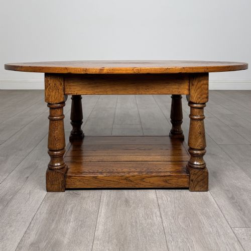 fig 4. An antique oval oak coffee table featuring four turned baluster legs and a solid lower undertier shelf.