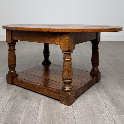 fig 5. An antique oval oak coffee table featuring four turned baluster legs and a solid lower undertier shelf.