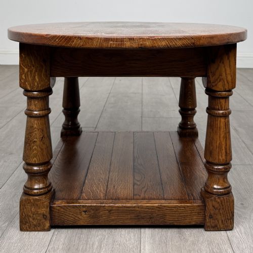 fig 6. An antique oval oak coffee table featuring four turned baluster legs and a solid lower undertier shelf.