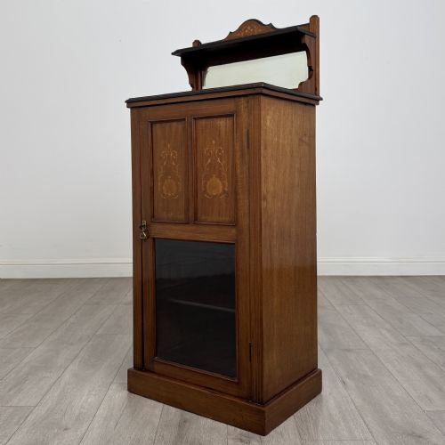 fig 2. An Edwardian inlaid mahogany cabinet featuring an upper mirrored gallery, two marquetry panels with shell motifs, and a glazed lower door section.