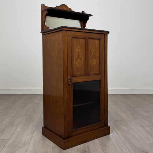 fig 8. An Edwardian inlaid mahogany cabinet featuring an upper mirrored gallery, two marquetry panels with shell motifs, and a glazed lower door section.