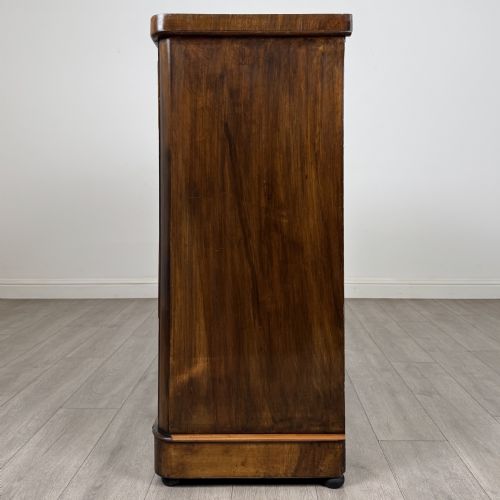 fig 2. An Edwardian walnut chest of drawers featuring two short drawers over three long drawers with ornate brass handles.