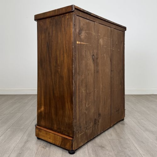 fig 3. An Edwardian walnut chest of drawers featuring two short drawers over three long drawers with ornate brass handles.