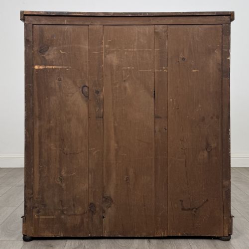 fig 4. An Edwardian walnut chest of drawers featuring two short drawers over three long drawers with ornate brass handles.