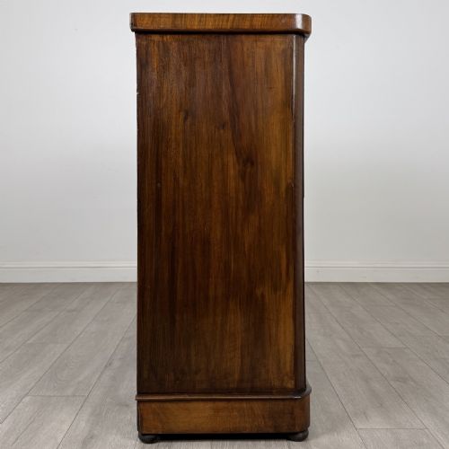 fig 6. An Edwardian walnut chest of drawers featuring two short drawers over three long drawers with ornate brass handles.