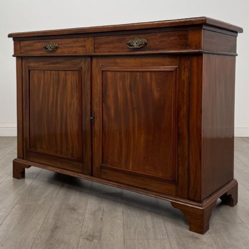fig 2. A Victorian mahogany cupboard featuring two drawers with brass drop handles above two panelled doors, resting on bracket feet.