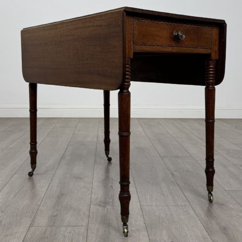 fig 6. An antique Regency style mahogany Pembroke side table featuring drop leaves, turned reeded legs, a single drawer with decorative inlay, and brass wheel castors.